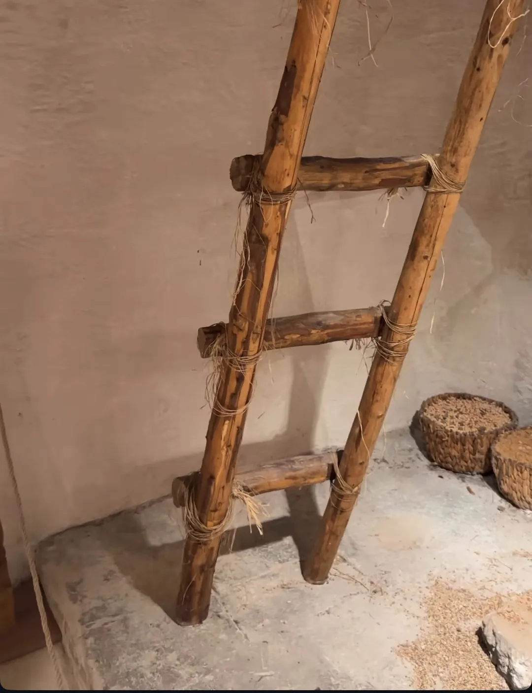 Çatalhöyük ev canlandırmasında çatıya çıkan ahşap merdiven, yerde hasır sepetler